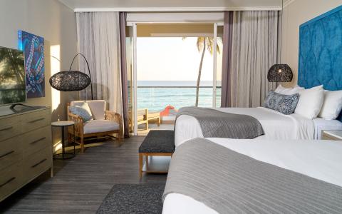 This image shows a modern and stylish hotel room with a direct view of the ocean