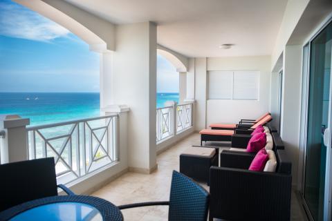 This image shows an elegant balcony of a coastal resort or apartment with a serene ocean view