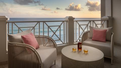 This image shows a cozy balcony set up overlooking a stunning ocean view