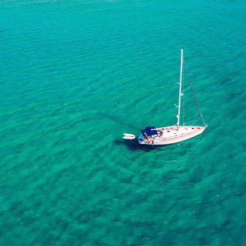 The image shows a sailboat floating on clear, turquoise waters