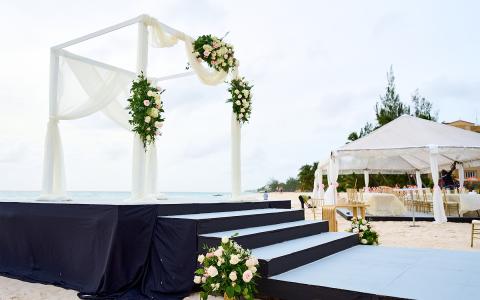 The image shows a beachside setup for a wedding ceremony