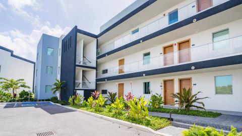 Modern multi-story apartment building with balconies and tropical landscaping