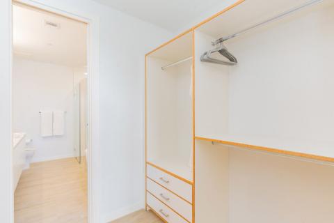 Organized Walk-In Wardrobe with Orange Accents and Adjoining Modern Bathroom