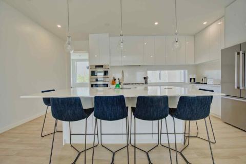 One Canal Point: Modern kitchen with white island, blue bar stools, and pendant lights