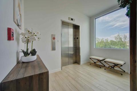 One Canal Point: Modern hallway with elevator, wooden bench, and large window view