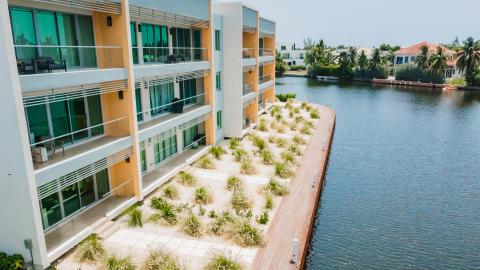 Modern Residential Building by Water with Garden and Boardwalk