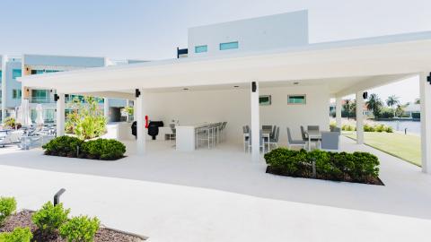 Modern outdoor area with dining and kitchen setup by water