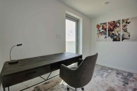 One Canal Point: Modern home office with dark wood desk, grey chair, and floral wall art