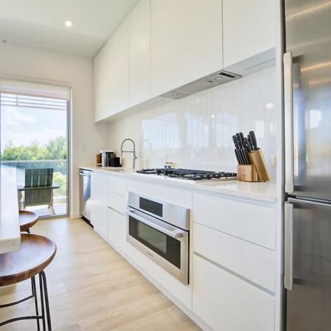 This image shows a modern kitchen featuring white cabinetry and a light wooden floor
