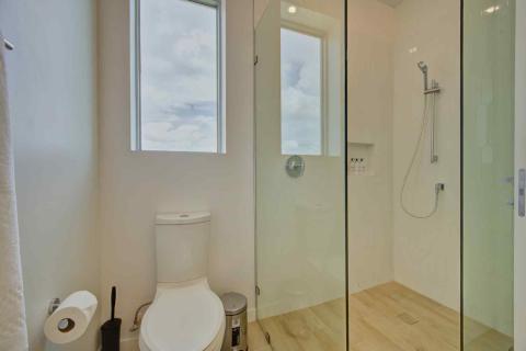 One Canal Point: Modern bathroom with glass-enclosed shower, white toilet, and light wood flooring  Title: One Canal Point: Modern bathroom with glass-enclosed shower, white toilet, and light wood flooring
