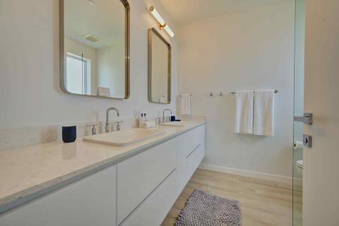 One Canal Point: Modern bathroom with dual-sink vanity, marble countertop, and light wood flooring  Title: One Canal Point: Modern bathroom with dual-sink vanity, marble countertop, and light wood flooring