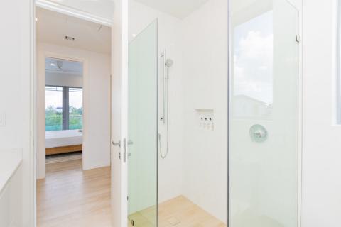 Modern bathroom with walk-in shower and view into bedroom