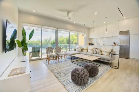 This image shows a modern, stylish living room with an open floor plan that extends into the kitchen area