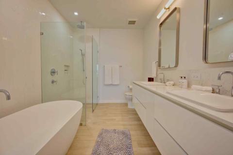 One Canal Point: Modern bathroom with freestanding bathtub, glass shower, and dual-sink vanity