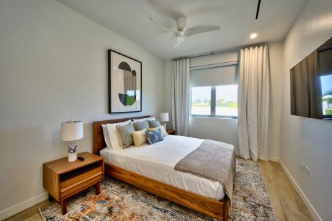 Modern bedroom with king-size bed, wooden frame, abstract artwork, ceramic lamps