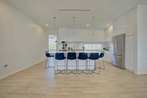 One Canal Point: Modern kitchen with white island, blue bar stools, and stainless steel appliances  Title: One Canal Point: Bright kitchen with island, blue bar stools, and contemporary design