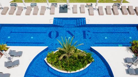 uxurious pool area with 'LOVE' mosaic design, sun loungers, and palm island.