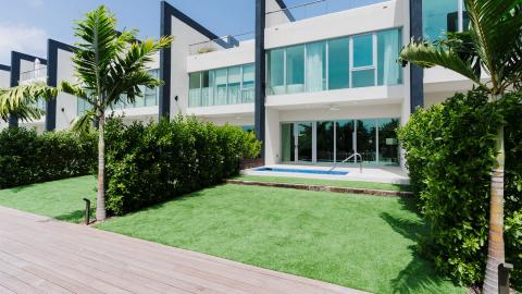 Modern luxurious villa with glass windows, lawn, and swimming pool