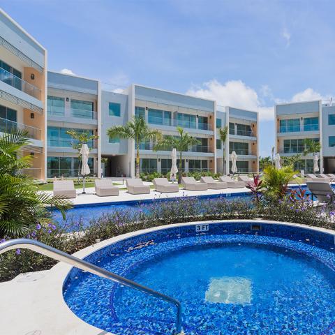 The image shows a modern resort or residential complex with a luxurious swimming pool area