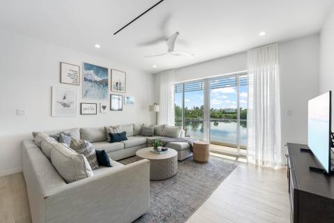 This is an image of a modern living room with a view of a body of water through large sliding glass doors