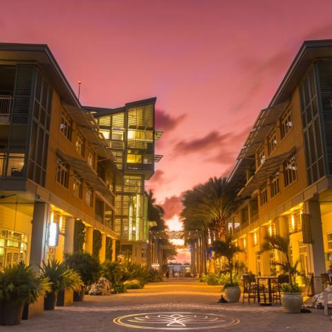 The image portrays a beautiful urban scene during twilight, featuring modern, multi-story buildings with prominent balconies and large windows