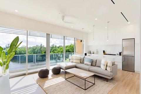 The image shows a modern, airy living room that flows into an open kitchen