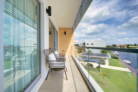 One Canal Point: Scenic balcony view with rattan chairs, green lawn, and waterfront