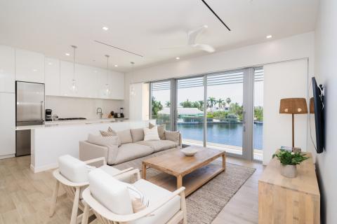 This image features a modern, open-plan living space that seamlessly connects a kitchen, dining area, and living room