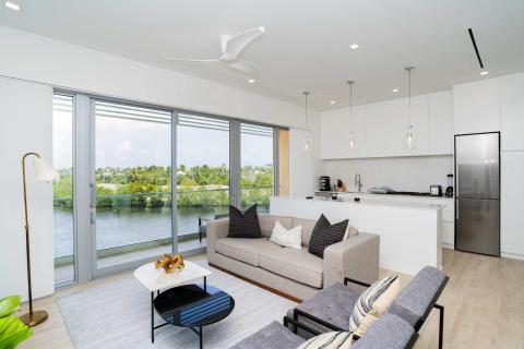 This image shows a modern, open-plan living room and kitchen area with a scenic view