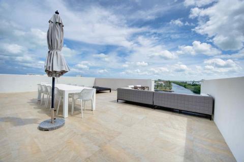 One Canal Point: Modern rooftop terrace with dining area, lounge, and scenic river view