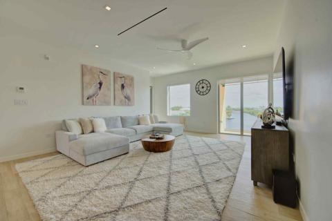 One Canal Point: Modern living room with sectional sofa, waterfront view, and artistic décor