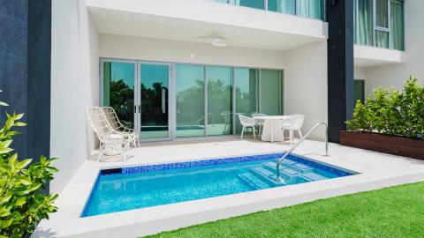 Modern outdoor area with rectangular pool, white patio furniture, sunny day.