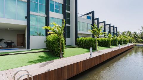 Modern residential buildings along a waterway with palm trees