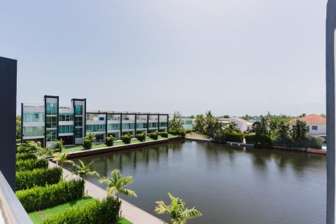 The image shows a modern residential area featuring stylish, multi-story buildings situated alongside a serene waterway
