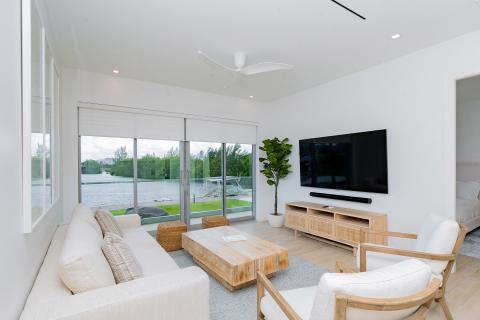 This image features a modern living room that overlooks a beautiful lake setting
