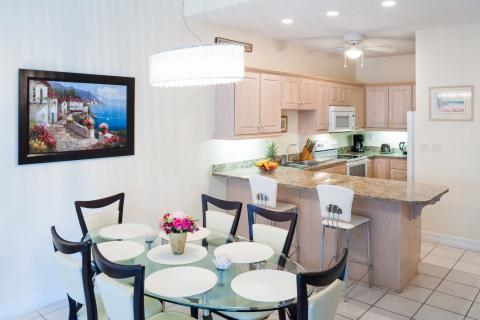  Neatly organized kitchen and dining area with glass table