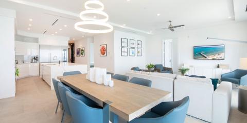 The image displays a modern and brightly lit living space that combines a dining area, kitchen, and living room into an open floor plan