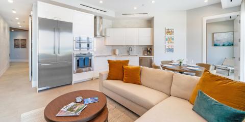 The image shows a modern, open-plan living space that includes a kitchen and a small dining area