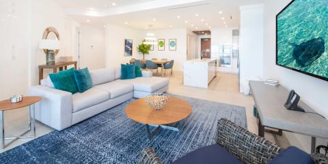 This image shows a modern and beautifully decorated living room connected to an open-plan kitchen and dining area