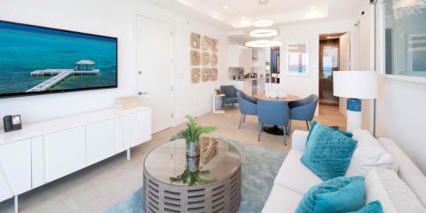 This image shows a modern and stylish living room with an open-layout design that extends into a dining area and an adjacent kitchen