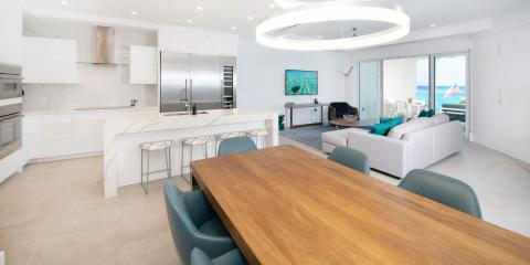 This image features a modern, luxurious open-plan living space that includes a kitchen and dining area that seamlessly flows into a living room