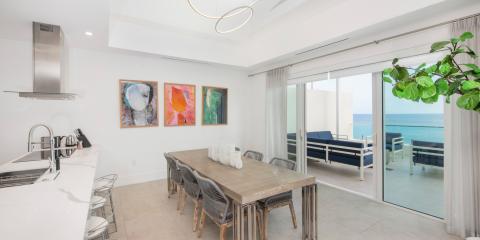 This image showcases a modern dining room adjacent to a kitchen, set in a home with a stunning ocean view