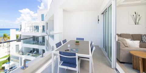 The image shows a modern balcony overlooking a beachfront
