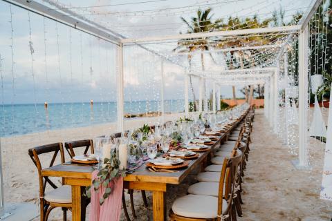 This image features an elegantly set outdoor dining area on a beach