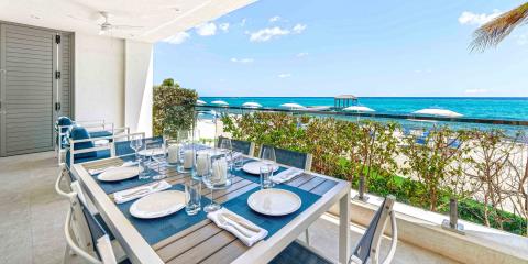 This image shows a beautifully set outdoor dining area on a terrace overlooking a beach