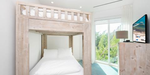 The image features a neatly arranged modern bedroom, notably including a large wooden bunk bed with the lower bunk holding a neatly made bed with white bedding