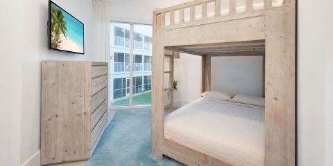 This image features a modern bedroom with a wooden bunk bed structure that accommodates a double bed on the bottom and a single bed on the top