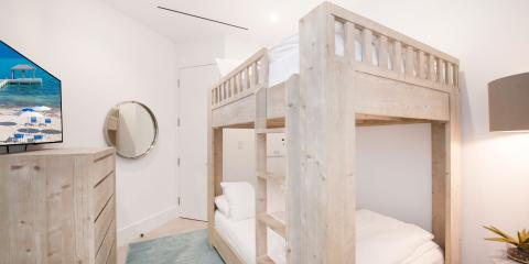 This image shows a modern bedroom designed for space efficiency, featuring a light-toned wooden bunk bed with a full bed below and a single bed on top