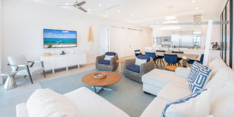 This image shows a modern, bright, and airy living area that transitions into a dining space and kitchen