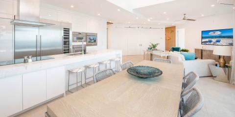 This image displays a modern, spacious kitchen and living area with a coastal decor theme
